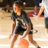 A young Black boy dribbles a basketball.